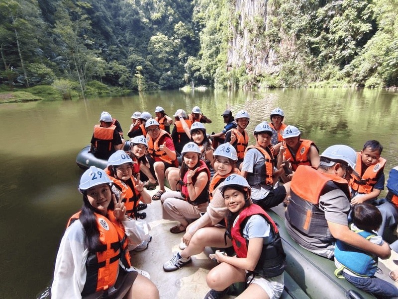 Maho, Reeracoen Malaysia Career Advisor, with a group riding a boat surrounded by lush forest during an outdoor team adventure